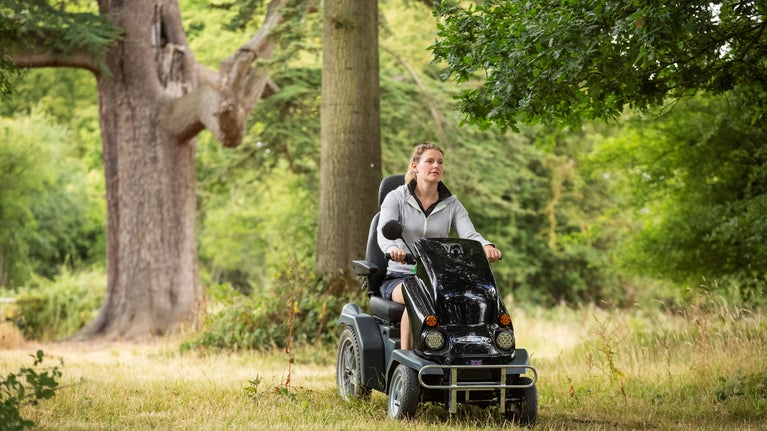 PMV user riding on a trail through trees